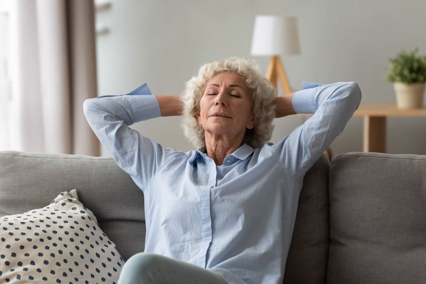 Elderly woman meditating with hands behind her head