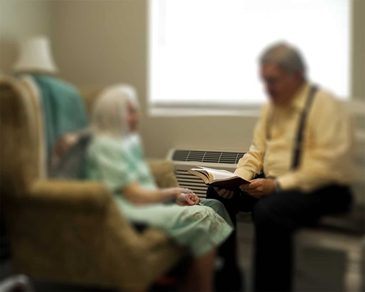 Elderly woman reading scripture with caregiver